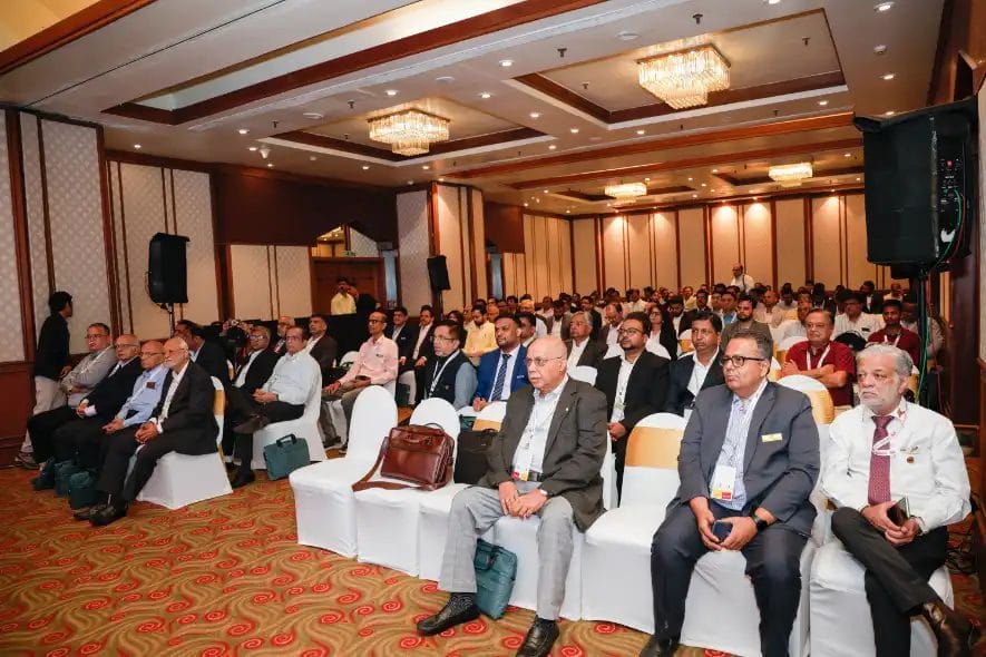 Conference attendees seated in a large meeting room.