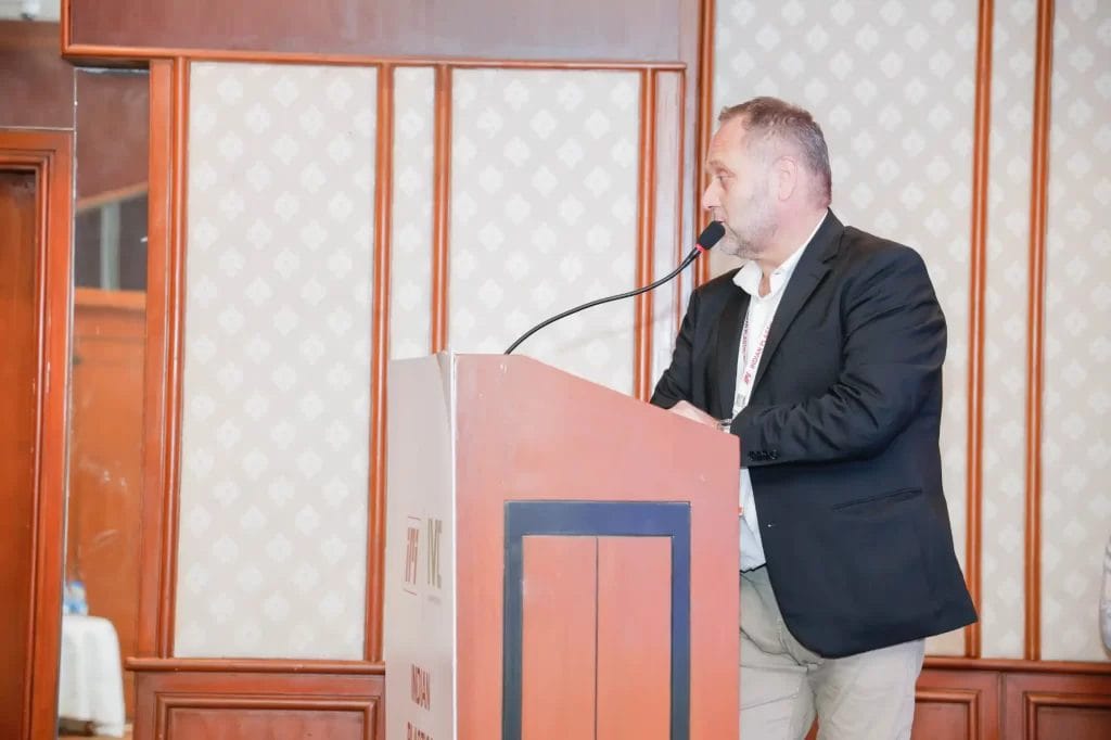 Man speaking at podium in conference room.