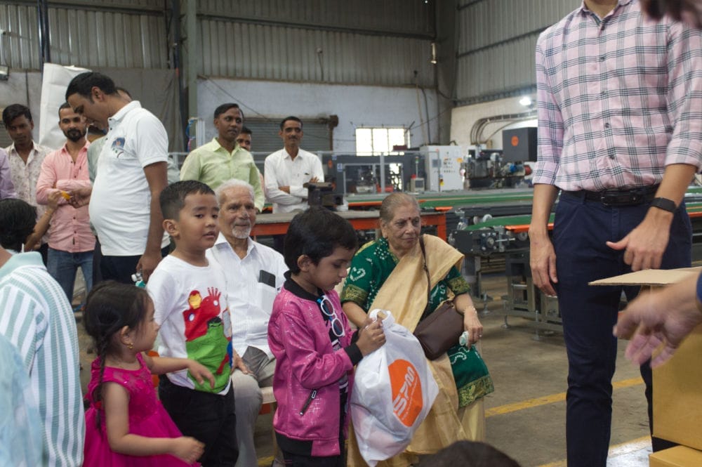 Group at factory, kids receiving gifts.
