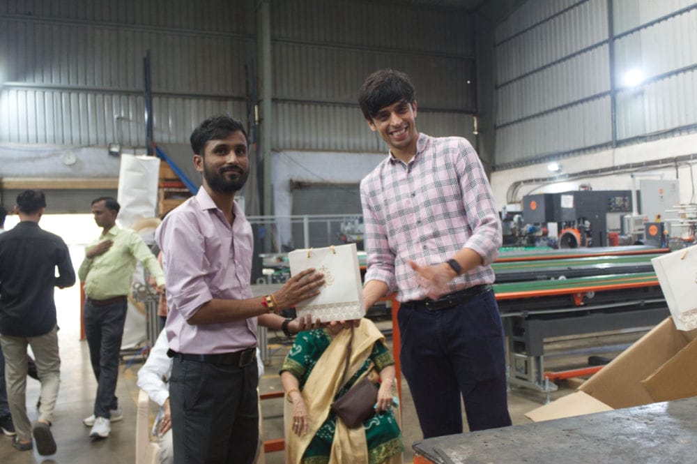 Men smiling and exchanging gift in a factory