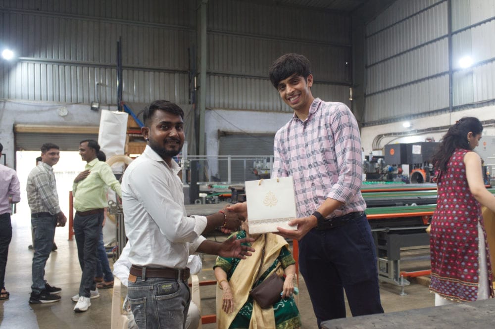 Two men exchanging a gift in an industrial setting.