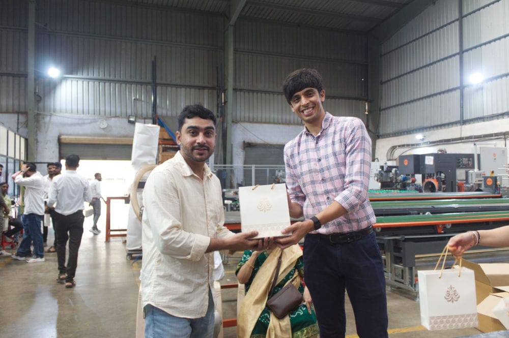 Two men exchanging gift bag in factory