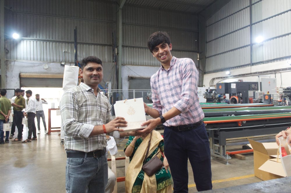 Two people exchanging a gift in a factory.