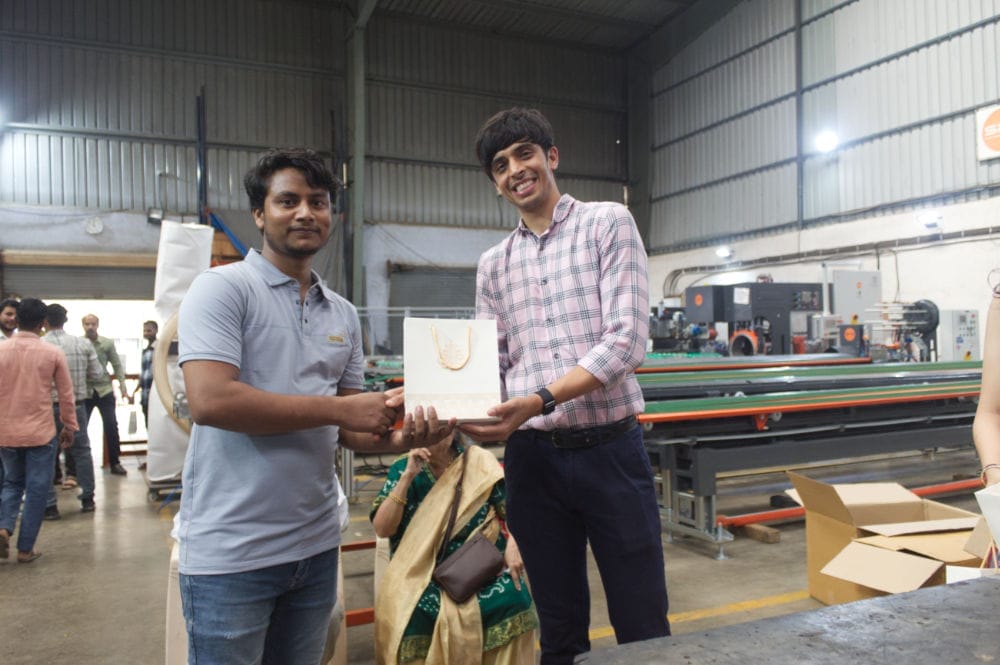 Two men holding a gift in a factory.