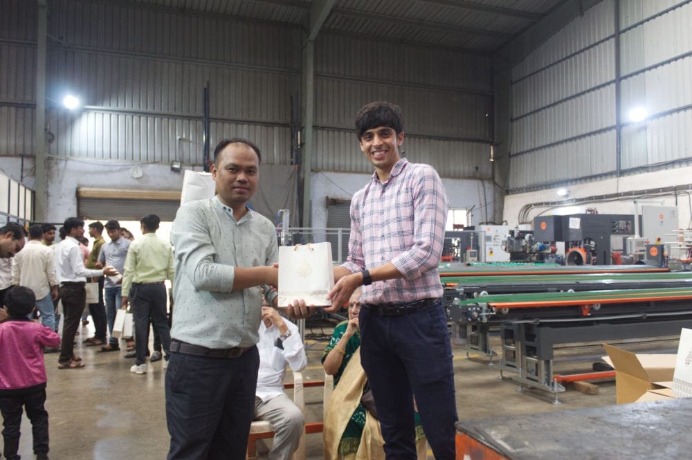 Two men exchanging a gift in a factory.