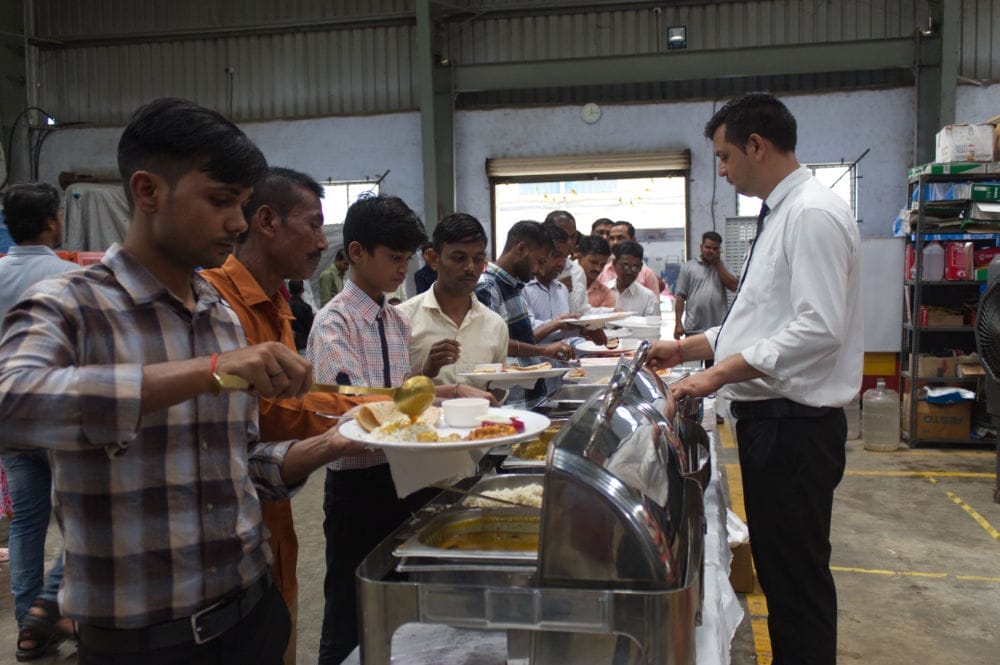 People serving food at a buffet line.