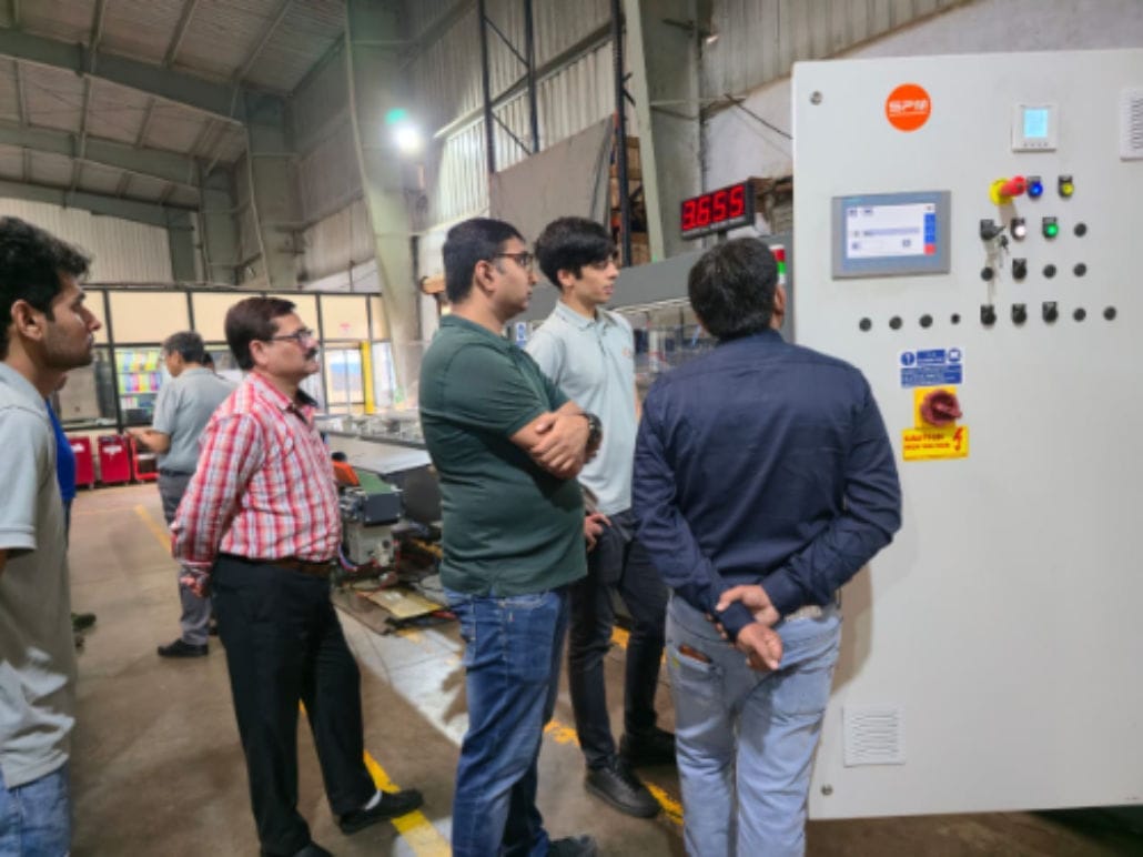 Group observing industrial control panel in factory